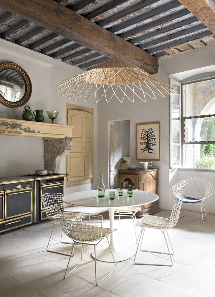 French country kitchen with rattan pendant light, round white Saarinen dining table, white Bertoia dining chairs