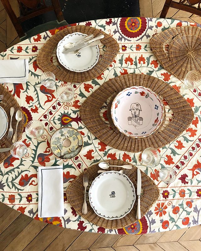Vintage red suzani tablecloth with rattan eye placemats. French table setting.
