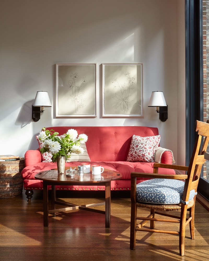 Sitting area designed by McGrath II with a red Tufted Ottoman and swing-arm sconces.