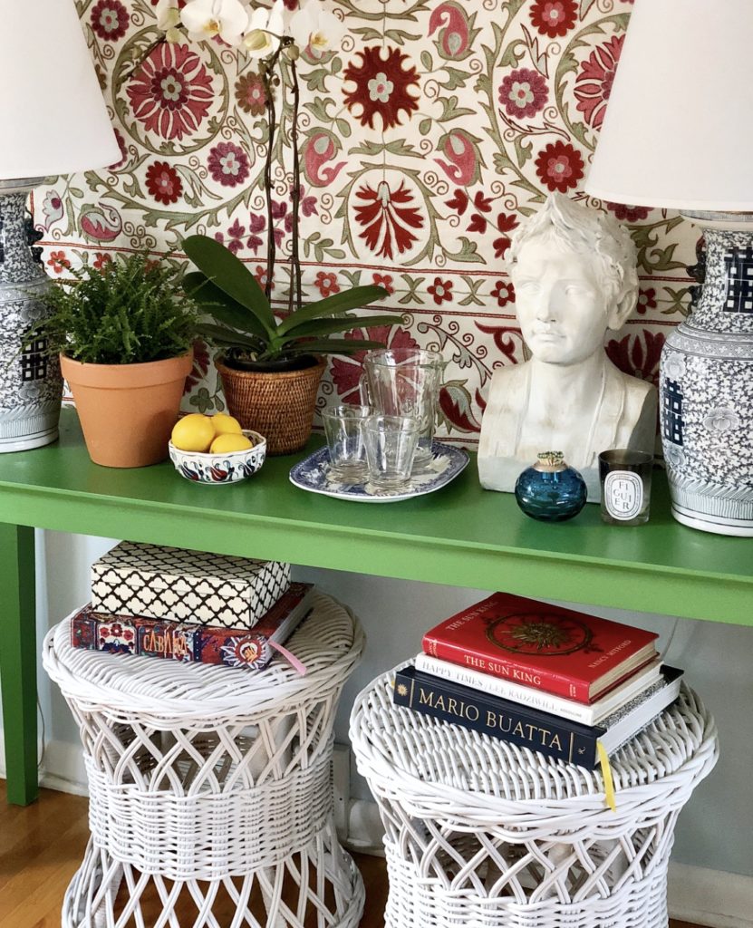 Green Console Table with Suzani Wall Hanging and Pair of White Wicker Ottomans