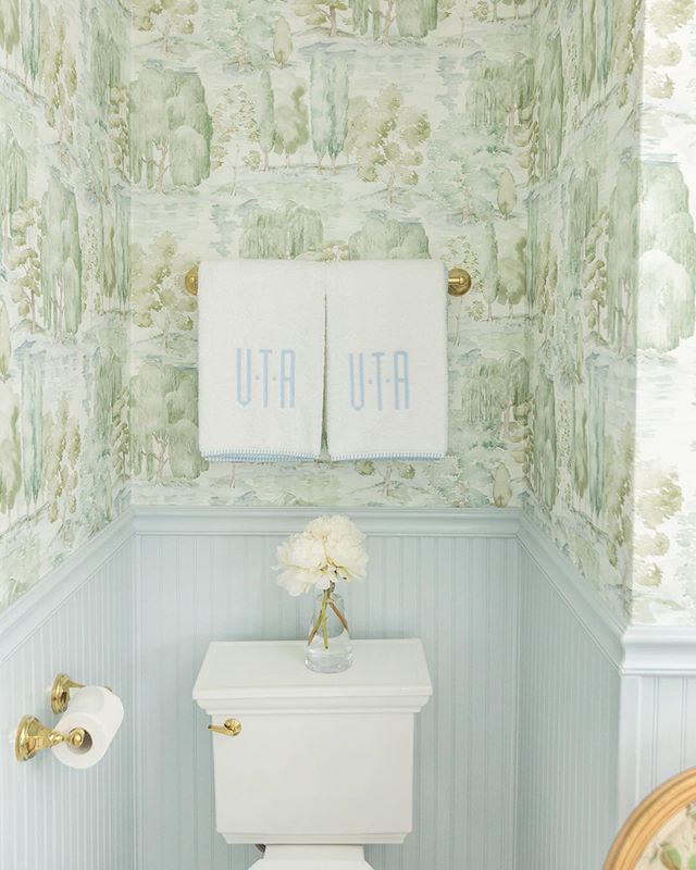 Bathroom with blue wainscoting and green scenic Sanderson wallpaper and monogrammed Weezie towels by Tori Alexander of Alexander Interiors in Nashville.